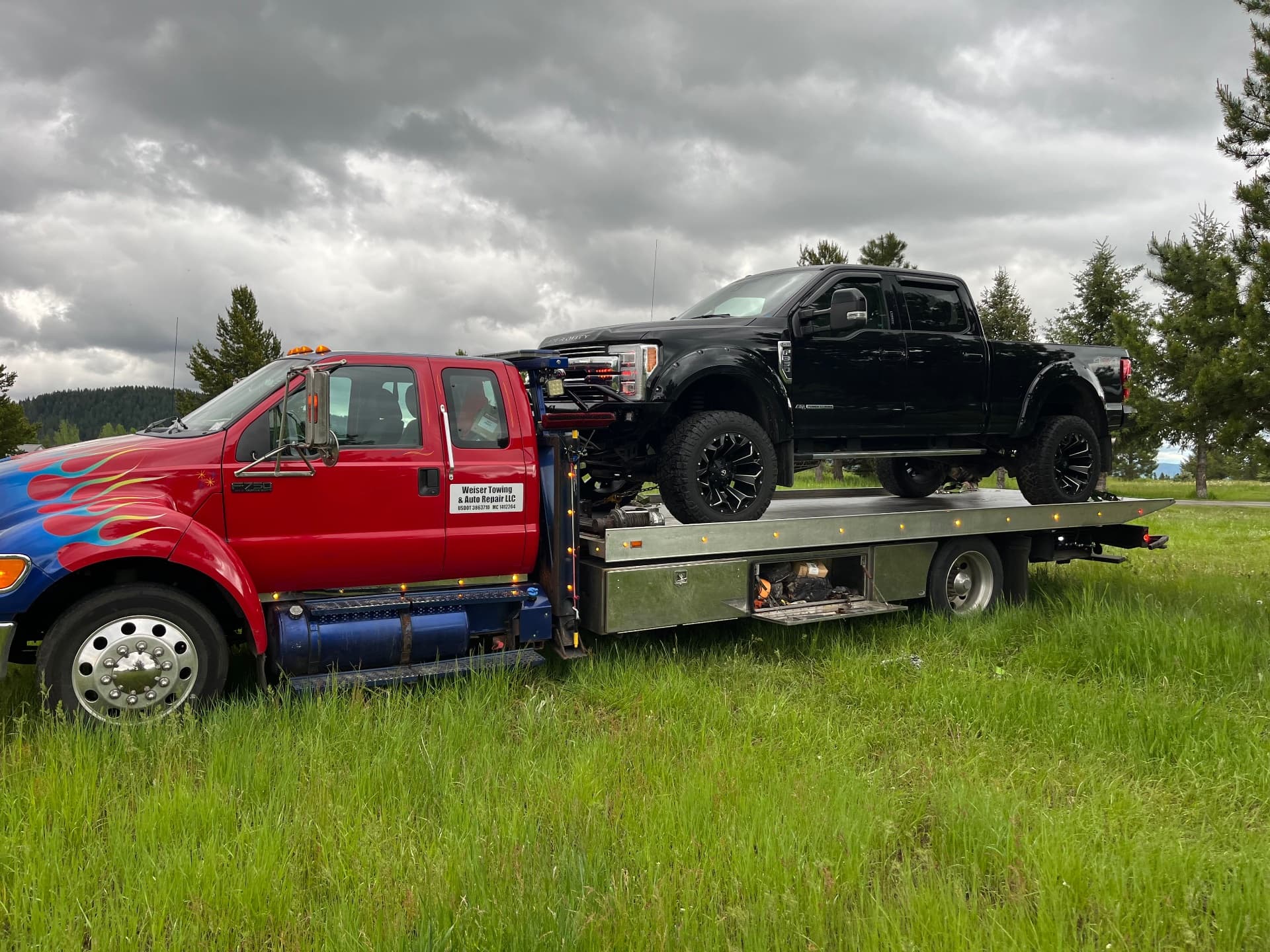 Weiser Towing red flatbed with black Ford truck in Idaho field