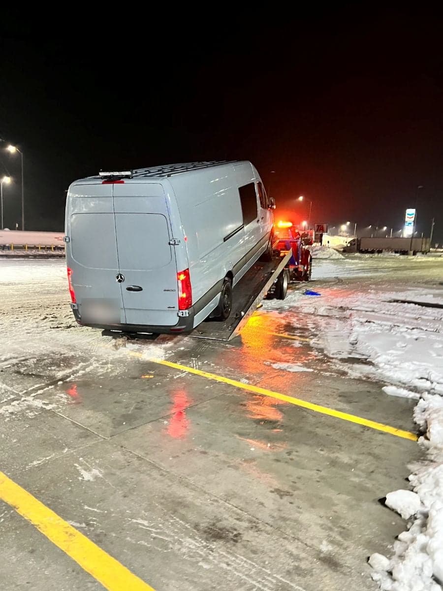 Weiser Towing flatbed loading a van at night on a snow-covered lot, amber lights on