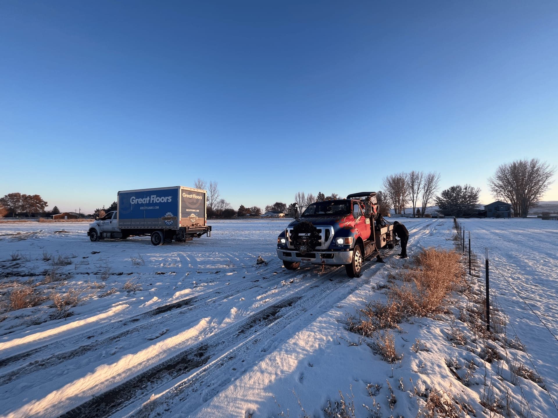 Weiser Towing wrecker recovering a box truck on a snowy Washington County field at dusk